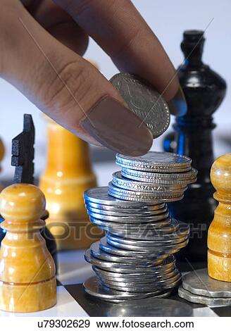 Stock Photo - Coins stacked on a chess board . Fotosearch