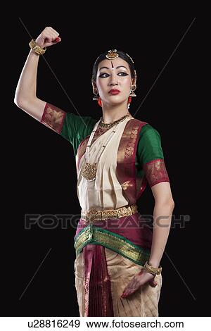 Stock Photo - Confident Bharatanatyam dancer flexing muscle over black background. Fotosearch
