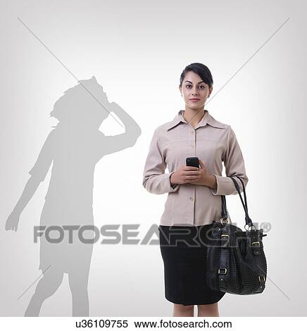 Stock Photography - Confident businesswoman standing in front of shadow dancing over gray background. Fotosearch