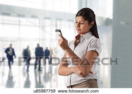 Confident businesswoman text messaging at office View Large Photo Image Stock Photo - Confident businesswoman text messaging at office . Fotosearch