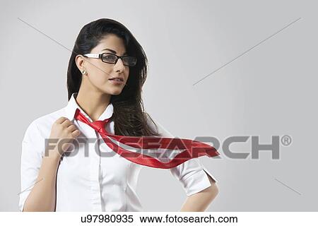 Confident fashionable businesswoman with windswept tie over gray background View Large Photo Image Stock Photography - Confident fashionable businesswoman with windswept tie over gray background. Fotosearch