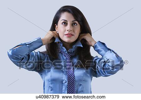 Stock Photo - Confident Indian businesswoman adjusting collar over gray background. Fotosearch