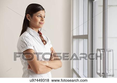 Stock Photo - Confident young business woman thinking while looking out . Fotosearch