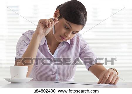 Confident young businesswoman busy reading document View Large Photo Image Stock Image - Confident young businesswoman busy reading document . Fotosearch