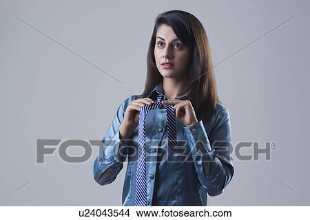 Confident young businesswoman getting dressed against gray background View Large Photo Image Picture - Confident young businesswoman getting dressed against gray background. Fotosearch
