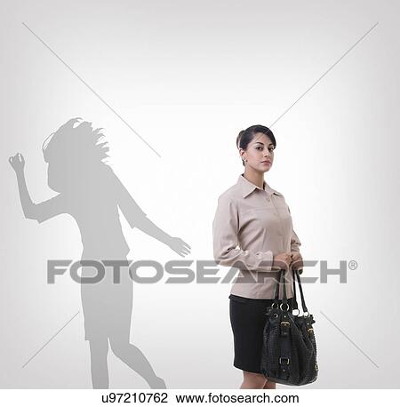 Confident young businesswoman standing in front of shadow dancing over gray background View Large Photo Image Stock Image - Confident young businesswoman standing in front of shadow dancing over gray background. Fotosearch