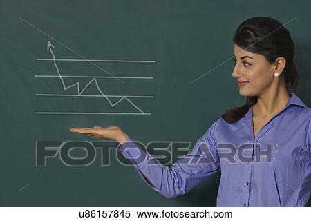Stock Photography - Confident young businesswoman displaying graph on green board at office. Fotosearch