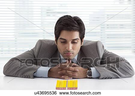 Stock Photograph - Confused male executive looking at pen and pencils . Fotosearch