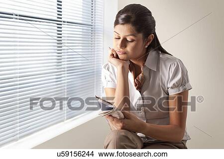 Picture - Confused young businesswoman solving puzzle on newspaper . Fotosearch