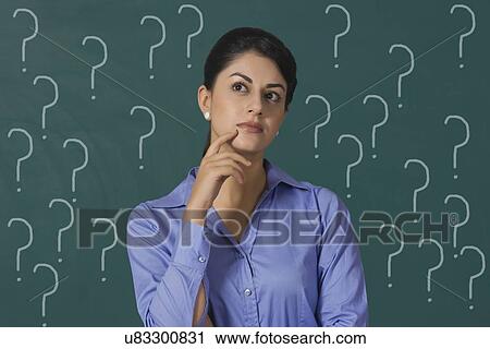 Confused young businesswoman standing against question marks on green board with question marks at office View Large Photo Image Stock Image - Confused young businesswoman standing against question marks on green board with question marks at office. Fotosearch