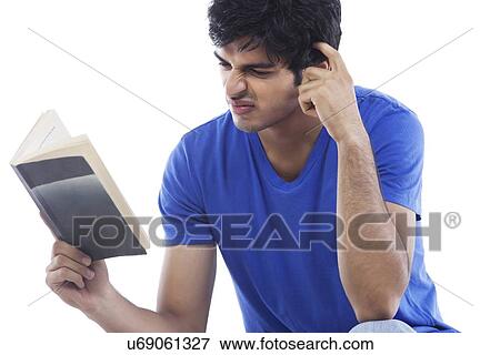 Confused young man reading book over white background View Large Photo Image Stock Photo - Confused young man reading book over white background . Fotosearch