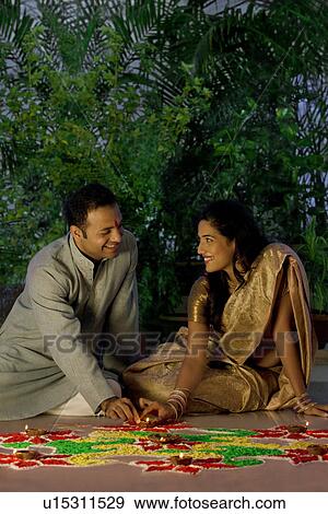 Stock Photo - Couple arranging diyas on a rangoli . Fotosearch