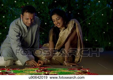 Couple arranging diyas on a rangoli View Large Photo Image Stock Photo - Couple arranging diyas on a rangoli . Fotosearch