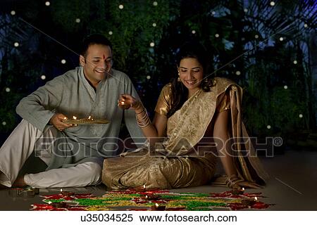 Stock Photography - Couple arranging diyas on a rangoli . Fotosearch