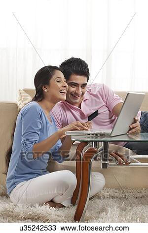 Stock Image - Couple enjoying while shopping online at home . Fotosearch