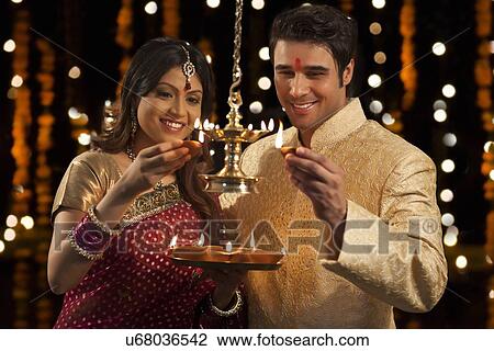 Couple lighting diyas View Large Photo Image Stock Image - Couple lighting diyas . Fotosearch