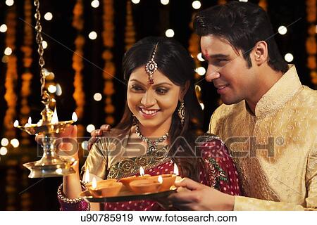 Couple lighting diyas View Large Photo Image Stock Photo - Couple lighting diyas. Fotosearch