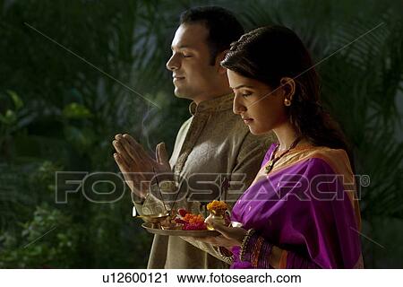 Stock Image - Couple praying during diwali . Fotosearch