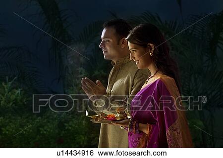Couple praying during diwali View Large Photo Image Stock Photograph - Couple praying during diwali . Fotosearch