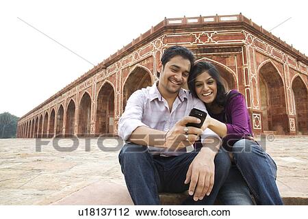 Stock Image - Couple reading an sms at Humayuns Tomb . Fotosearch