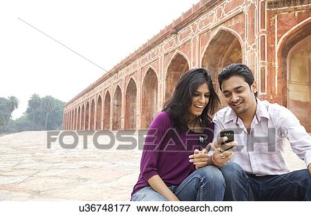 Stock Photo - Couple reading an sms at Humayuns Tomb . Fotosearch