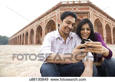 Stock Photo - Couple reading an sms at Humayuns Tomb . Fotosearch