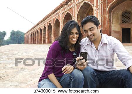 Stock Photography - Couple reading an sms at Humayuns Tomb . Fotosearch