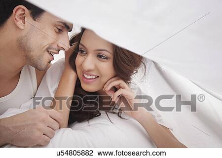 Stock Image - Couple romancing in bed. Fotosearch
