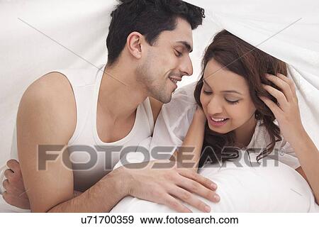 Couple romancing in bed View Large Photo Image Stock Photo - Couple romancing in bed. Fotosearch