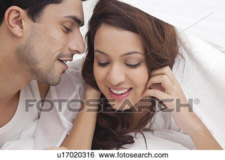 Couple romancing in bed View Large Photo Image Stock Photograph - Couple romancing in bed. Fotosearch
