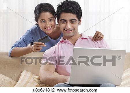 Stock Image - Couple using laptop for online shopping . Fotosearch
