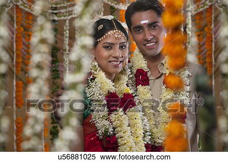 Couple wearing garlands standing together during traditional Indian wedding View Large Photo Image Stock Photography - Couple wearing garlands standing together during traditional Indian wedding . Fotosearch