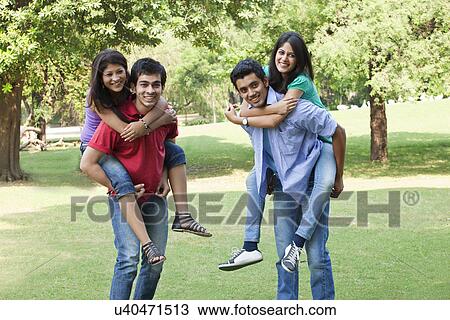 Stock Image - Couples piggybacking on campus and looking away . Fotosearch