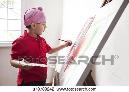 Stock Image - Cute little boy painting on artist's canvas with paintbrush . Fotosearch