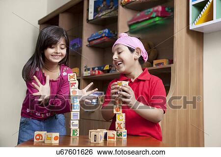 Stock Photograph - Cute little brother and sister playing with wooden toy blocks . Fotosearch