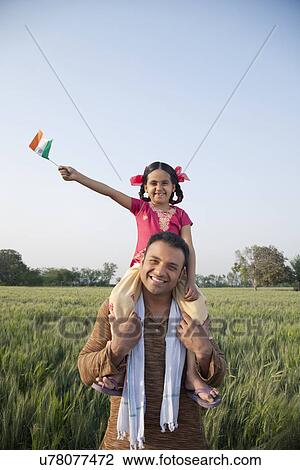 Daughter sitting on father's shoulders with the Indian flag in an agricultural field View Large Photo Image Stock Image - Daughter sitting on father's shoulders with the Indian flag in an agricultural field . Fotosearch