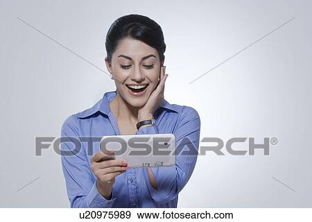 Delighted young businesswoman using digital tablet against gray background View Large Photo Image Stock Photo - Delighted young businesswoman using digital tablet against gray background. Fotosearch
