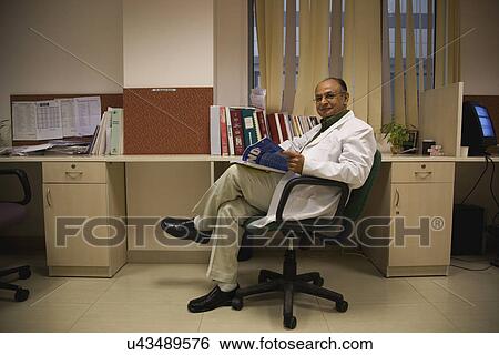 Stock Photograph - Doctor sitting with a magazine . Fotosearch