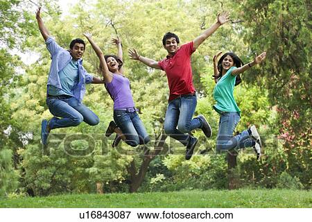 Stock Photo - Excited young college students jumping in lawn . Fotosearch