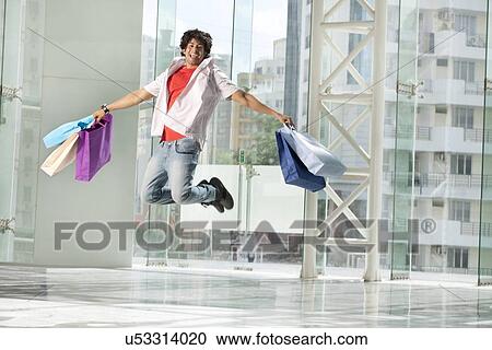 Excited young man jumping with shopping bags View Large Photo Image Stock Image - Excited young man jumping with shopping bags . Fotosearch