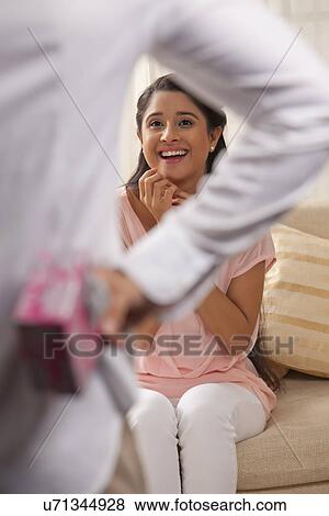 Excited young woman looking at man holding gift View Large Photo Image Stock Photo - Excited young woman looking at man holding gift . Fotosearch