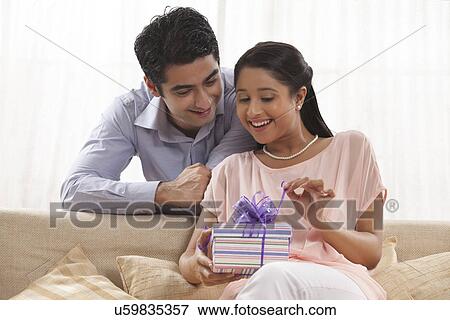Excited young woman unwrapping the gift at home View Large Photo Image Stock Photo - Excited young woman unwrapping the gift at home . Fotosearch