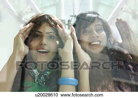 Excited young women peeking through window View Large Photo Image Stock Image - Excited young women peeking through window . Fotosearch