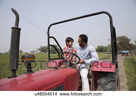 Picture - Father and little boy looking at each other while sitting in a tractor . Fotosearch