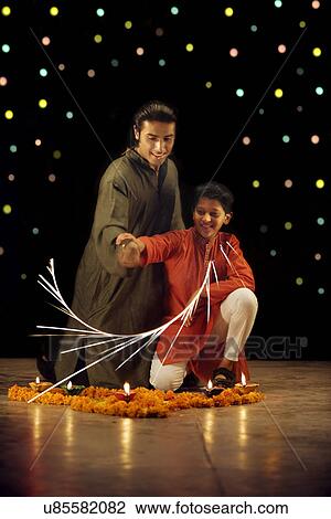Stock Image - Father and son burning crackers . Fotosearch