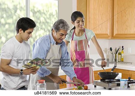 Father cutting vegetables while his daughter cooks View Large Photo Image Stock Photo - Father cutting vegetables while his daughter cooks . Fotosearch