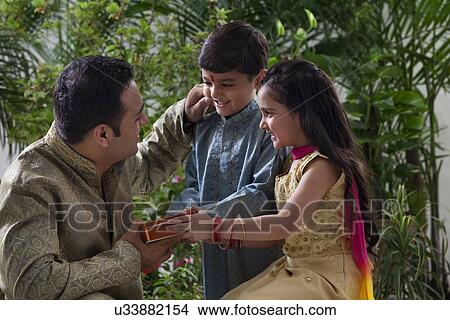 Father giving his kids chocolates View Large Photo Image Picture - Father giving his kids chocolates . Fotosearch