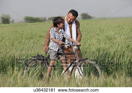 Father guiding son to ride cycle in the field View Large Photo Image Stock Image - Father guiding son to ride cycle in the field . Fotosearch