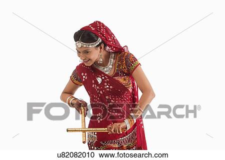 Stock Image - Female dandiya dancer dancing with sticks . Fotosearch