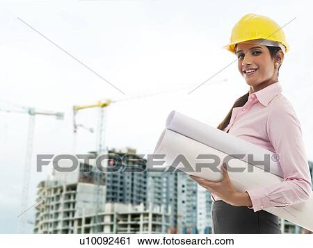 Stock Image - Female engineer with blueprints . Fotosearch